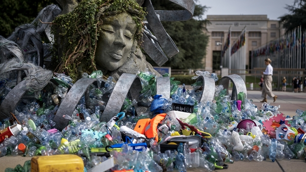 Plastics items are seen lying next to an artwork by Canadian artist Benjamin Von Wong entitled "The Thinker's Burden" in Geneva