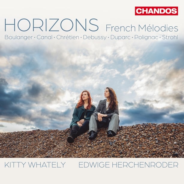 Kitty Whately and Edwidge Herchenroder sitting under a cloud-flecked sky