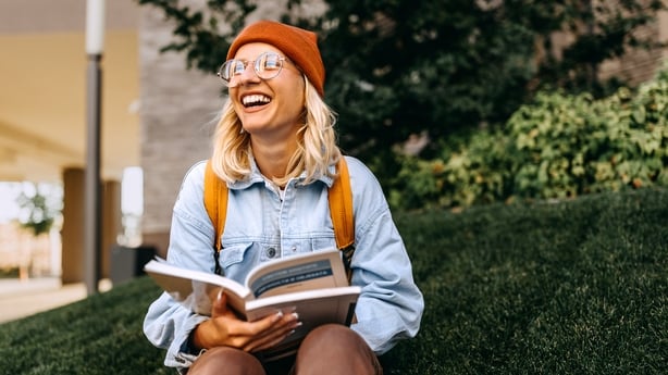 Young cheerful hipster woman studying outdoors in campus