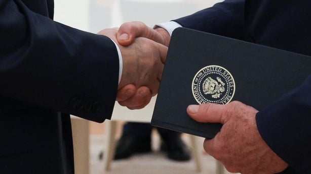 Vladimir Putin shakes hands with Steve Witkoff who holds a folder with a US Presidential seal visible