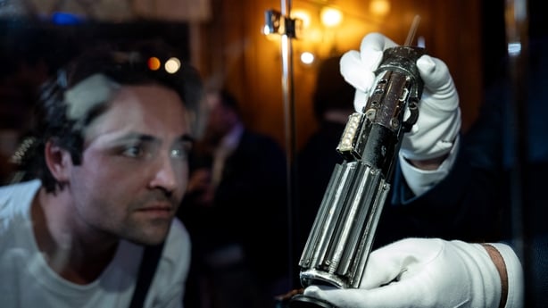 A person looks at the lightsaber of the character Darth Vader from the films Star Wars: The Empire Strikes Back and Return of the Jedi during a press preview of movie props set to go to auction