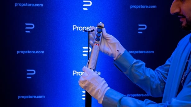 A staff member holds The Nuralyzer from the film Men in Black during a press preview of movie props set to go to auction