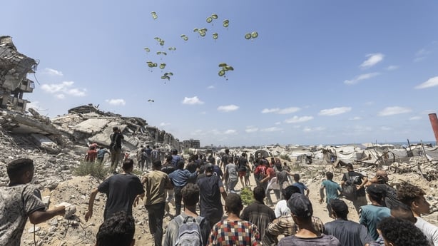 Planes drop aid packages by parachute amid Israeli attacks as the Palestinians run to the area where aid packages land over western Gaza City