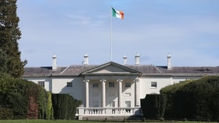 A photo of Aras an Uachtarain, with the Irish flag above and blue skies