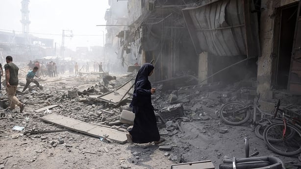 A Palestinian woman walks amid the rubble following an Israeli strike that hit Gaza City