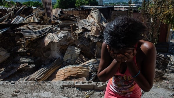 A woman cries with her head in her hands outside her burning house in the Post Marchand neighborhood of Port-au-Prince, Haiti