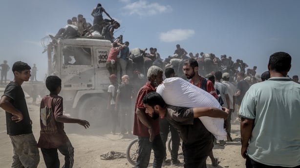 Palestinians gather near the Zikim Crossing to receive limited aid supplies in northwestern Gaza