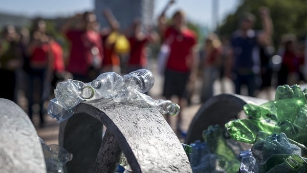 plastic bottles displayed as activists stage a demonstration in the background
