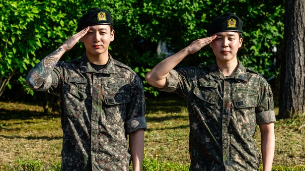Jungkook and Jimin of K-pop supergroup BTS in military uniform salute