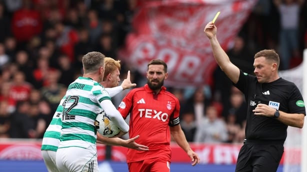 ABERDEEN, SCOTLAND - AUGUST 10: Referee John Beaton shows a yellow card to Celtic's Liam Scales and Callum McGregor protests during a William Hill Premiership match between Aberdeen and Celtic at Pittodrie, on August 10, 2025, in Aberdeen, Scotland. (Photo by Craig Williamson/SNS Group via Getty Ima