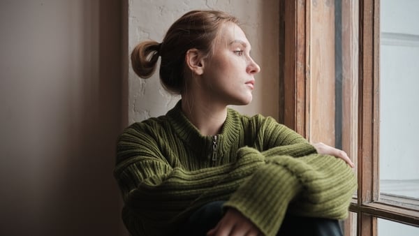 Sad woman at home looking out window