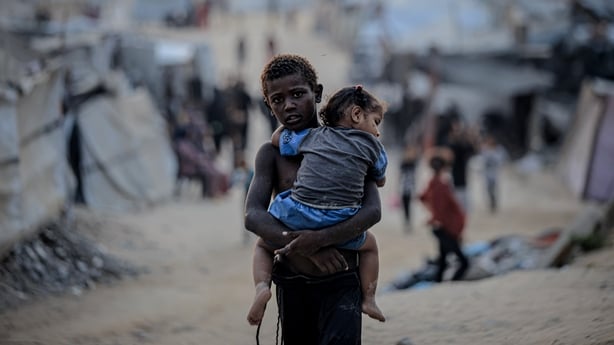 A boy holds his sister as Palestinians, deprived of basic necessities such as shelter, food, and clean water, struggle to survive in harsh living conditions in Gaza City