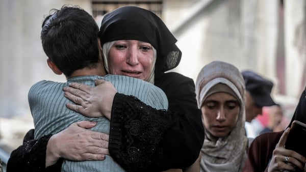 A woman wearing black hugs a child while crying in Gaza