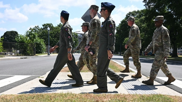 Six people dressed in military uniform use a zebra crossing to cross a road in Washington