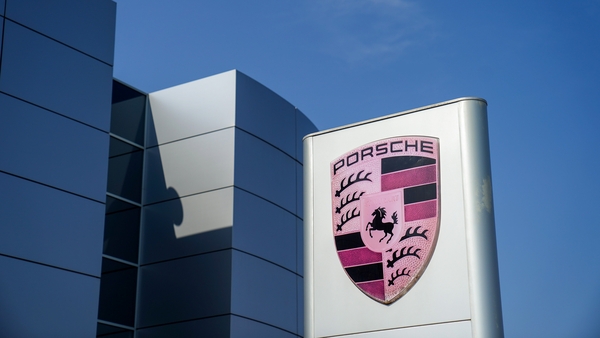 Porsche AG logo outside a car dealership against a bright blue sky