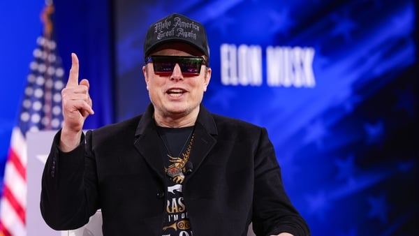 Elon Musk wearing a baseball cap and sunglasses speaks at the Conservative Political Action Conference
