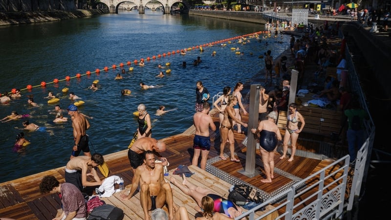 People swim and sunbath at the Bras Marie safe bathing site on the Seine river in Paris
