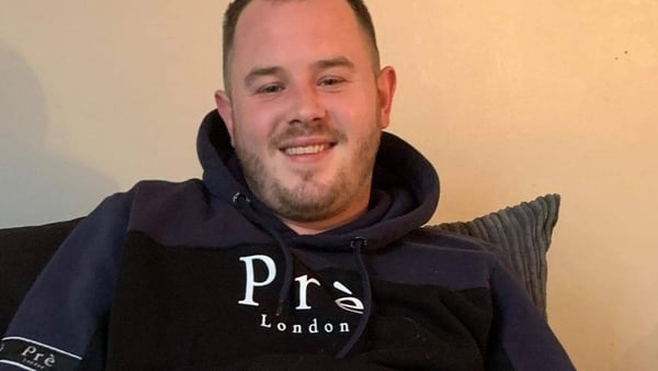 A man wearing a black hoodie smiles a the camera for a photo