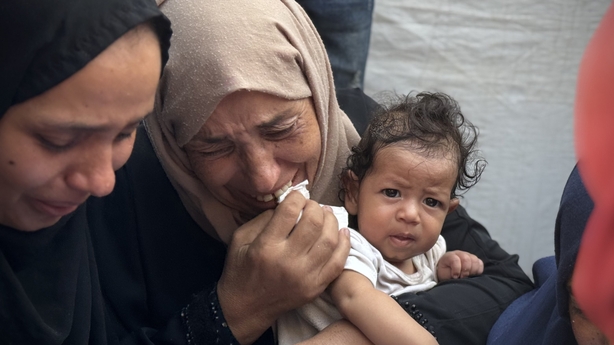 KHAN YUNIS, GAZA - AUGUST 14: A woman holds a baby while crying after an Israeli army attack on the Morag area in the northern part of Rafah, Gaza Strip, which left casualties and injured people, on August 14, 2025. The bodies of those killed in the attack were brought to Nasser Hospital in Khan Yun