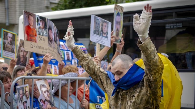 A Ukrainian serviceman released from Russian captivity with bandaged hands greets people during a POW exchange last month