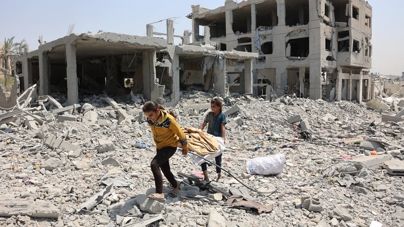 Palestinian girls carry salvaged items across debris and rubble in the al-Tuffah neighbourhood of Gaza City
