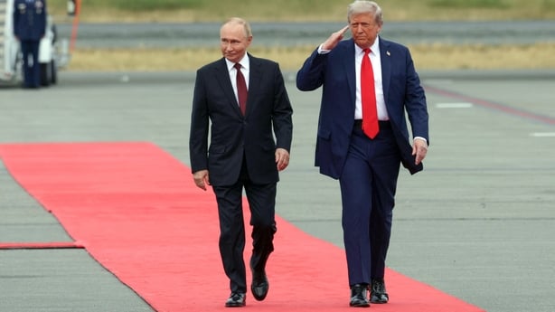 Donald Trump salutes as he and Vladimir Putin walk on the tarmac after their arrival for a US-Russia summit on Ukraine in Alaska