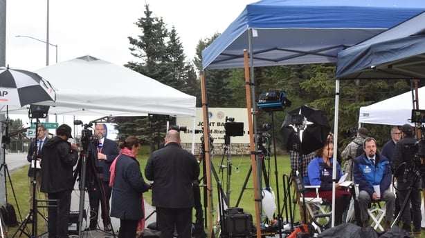 A crowd of reporters gather at the entrance of Joint Base Elmendorf-Richardson in Anchorage, Alaska