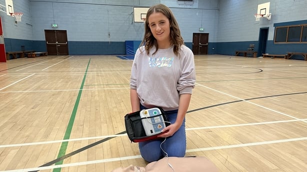 Cliodhna Ward pictured holding an AED in a sports hall