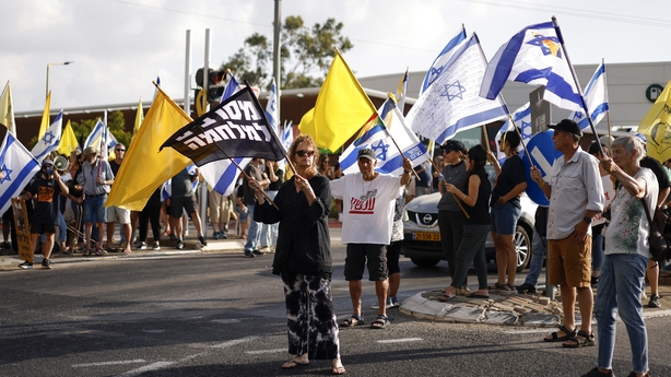 Israelis wave national and yellow flags as they protest against their government demanding a deal to release Israeli hostages held in Gaza by Hamas near the northern town Kiryat Shmona