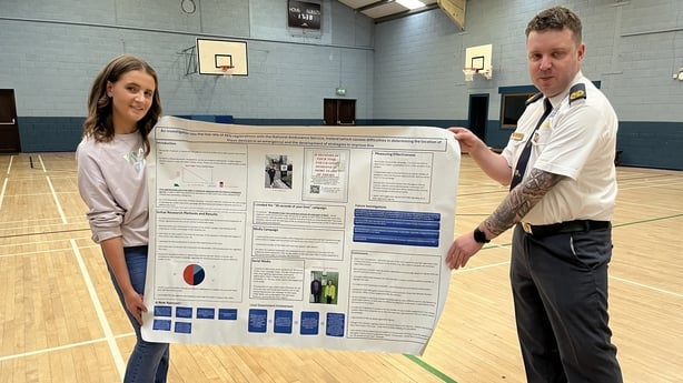 Cliodhna Ward and Liam Stewart hold up a sign in a sports hall