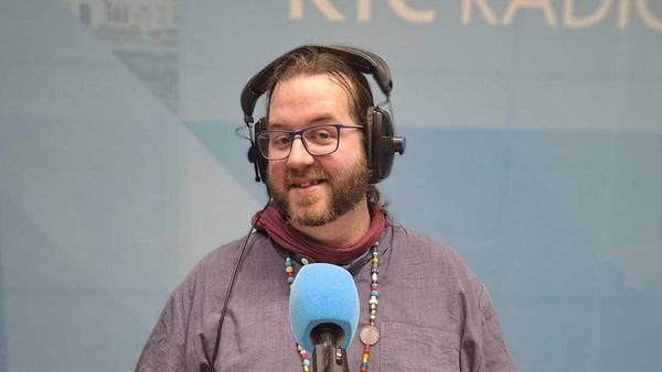 Oein deBharduin in studio for Sunday Miscellany, behind mic, looking straight into camera