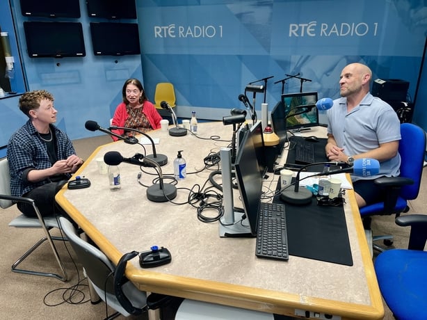 Three people chatting around a table with microphones set up