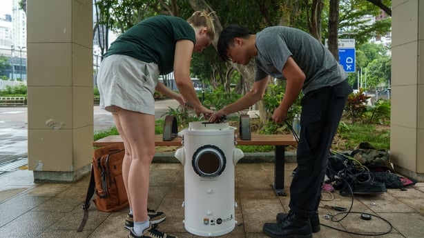 A man and a woman examine a cylinder 