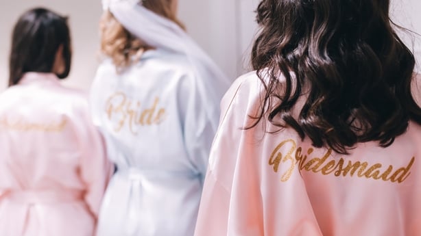 Back view of a group of bridesmaids with the bride-to-be in beautiful silk robes with different names on the back.