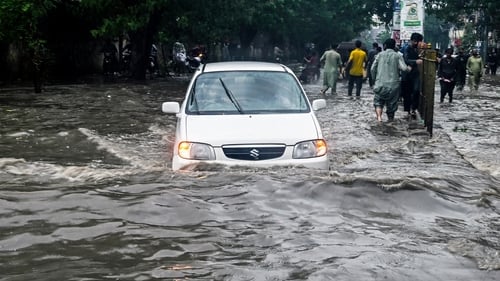 People wade through a flooded street after heavy rainfall in Karachi, Pakistan