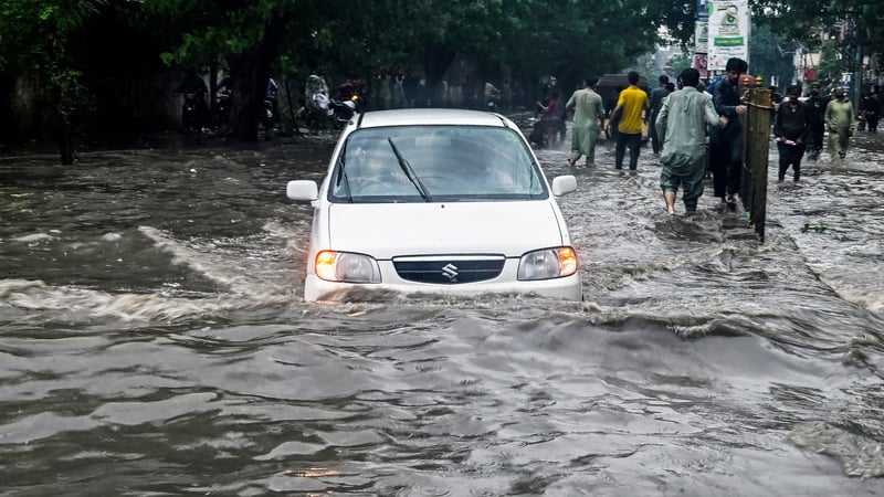 People wade through a flooded street after heavy rainfall in Karachi, Pakistan