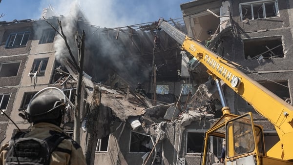 A firefighter and a crane are seen in front of a destroyed building in Ukraine