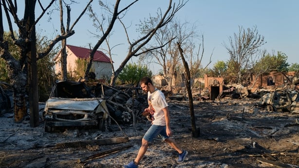 A local resident walks through the site of a Russian Shahed drone strike that destroyed vehicles and residential buildings in Sloviansk, Ukraine