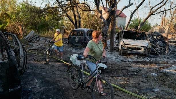 Local residents walk through the site of a Russian Shahed drone strike that destroyed vehicles and residential buildings in Sloviansk, Ukraine