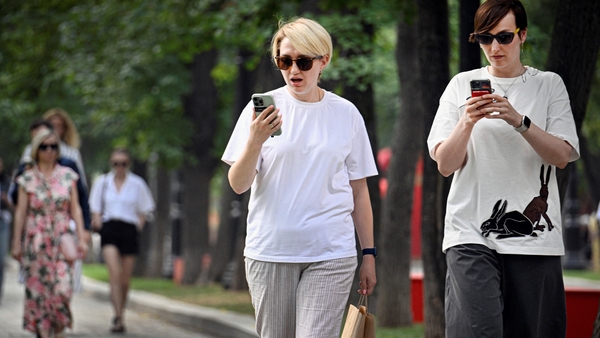Pedestrians with sunglasses use smart phones