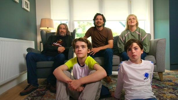 A Family sit watching the TV.