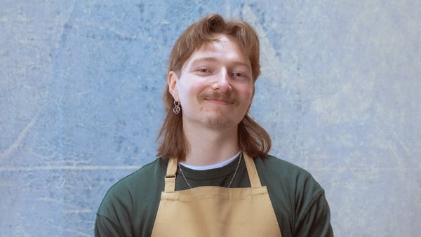 Man smiling at the camera, wearing a beige baking apron