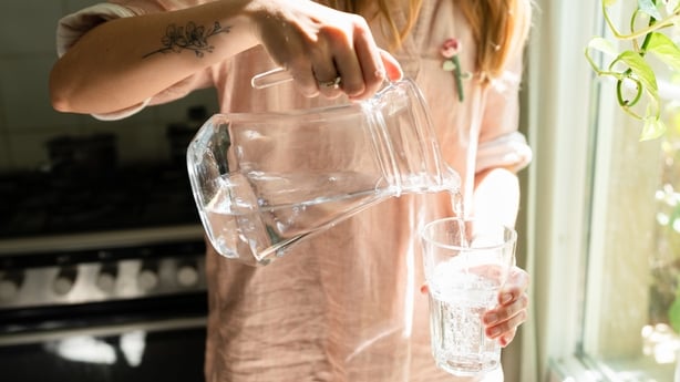 A woman fills a glass with drinking water