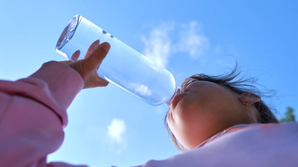 A girl drinks water from a transparent water bottle