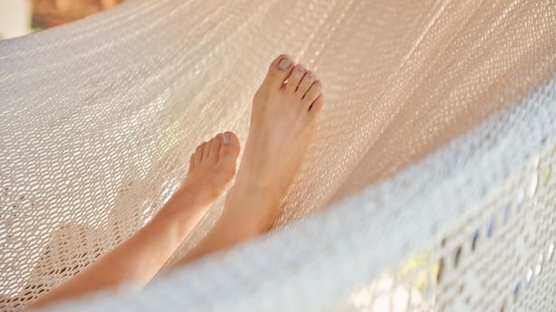 A barefoot person resting in a hammock