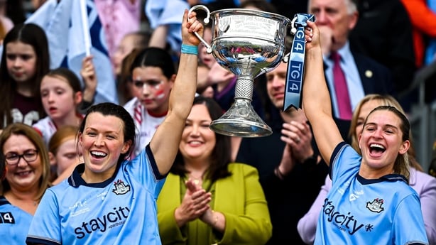 Dublin players Leah Caffrey, left, and Martha Byrne lift the Brendan Martin Cup after defeating Meath in 2025 All-Ireland final