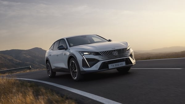 Photo of a white car driving on a road at sunset