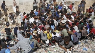 crowds of people search though dusty roads in search of food in Gaza