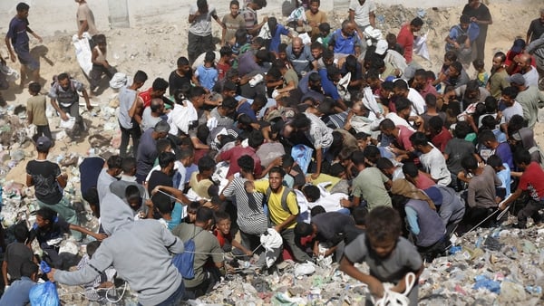 crowds of people search though dusty roads in search of food in Gaza