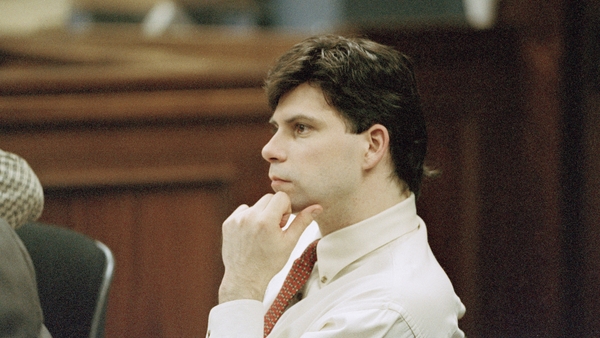 A man in a tie sits in a court room